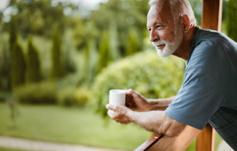 Retired Man Leaning On Balcony Having Coffee