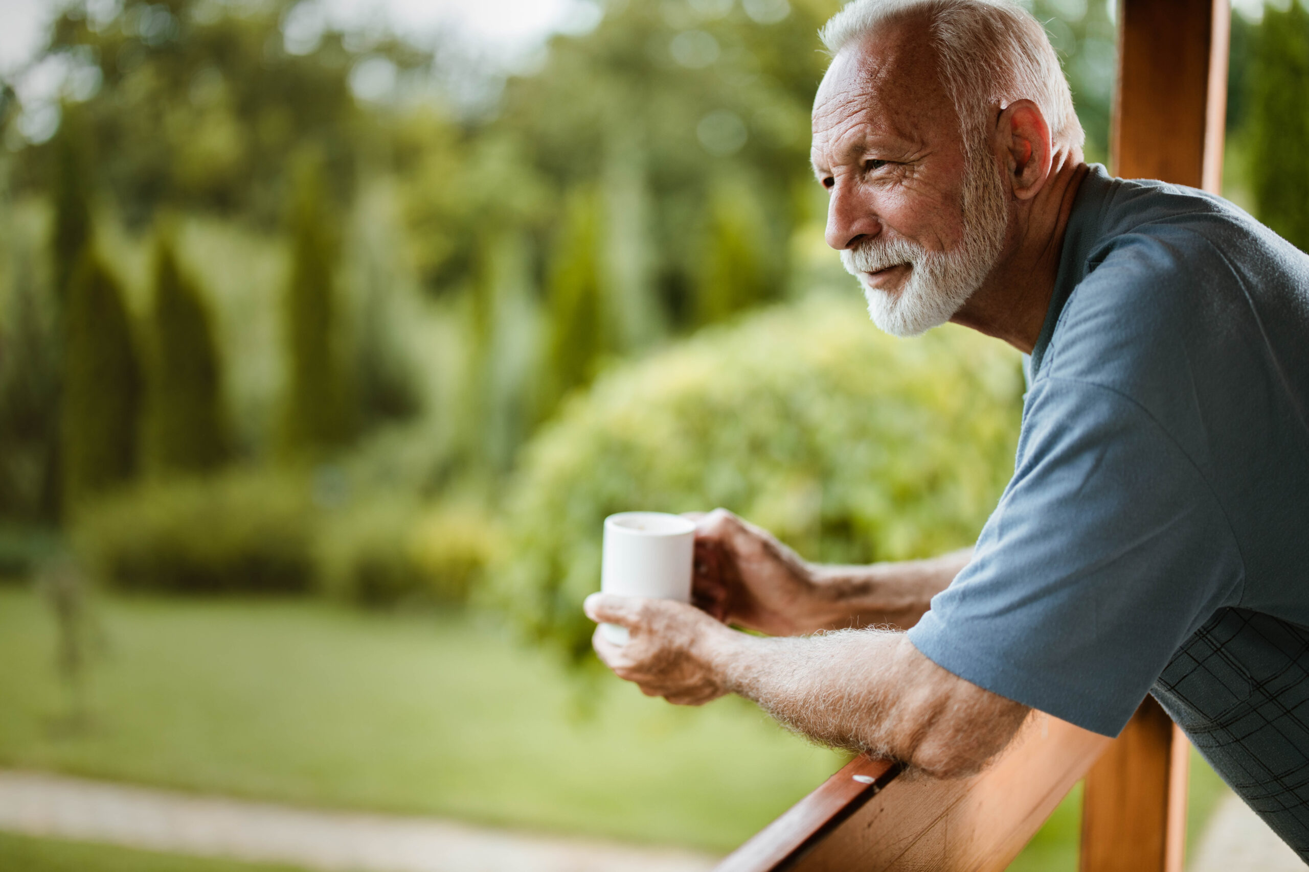 Retired man leaning on balcony having coffee