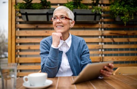 Smiling Mature Woman Using Digital Tablet While Drinking A Coffee