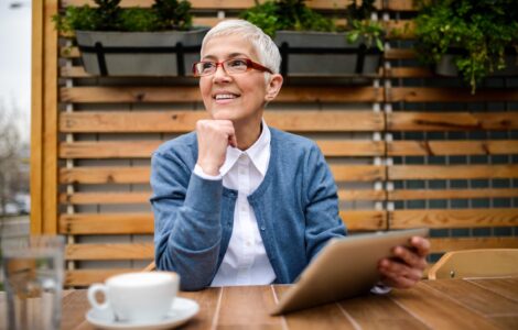 Smiling Mature Woman Using Digital Tablet While Drinking A Coffee