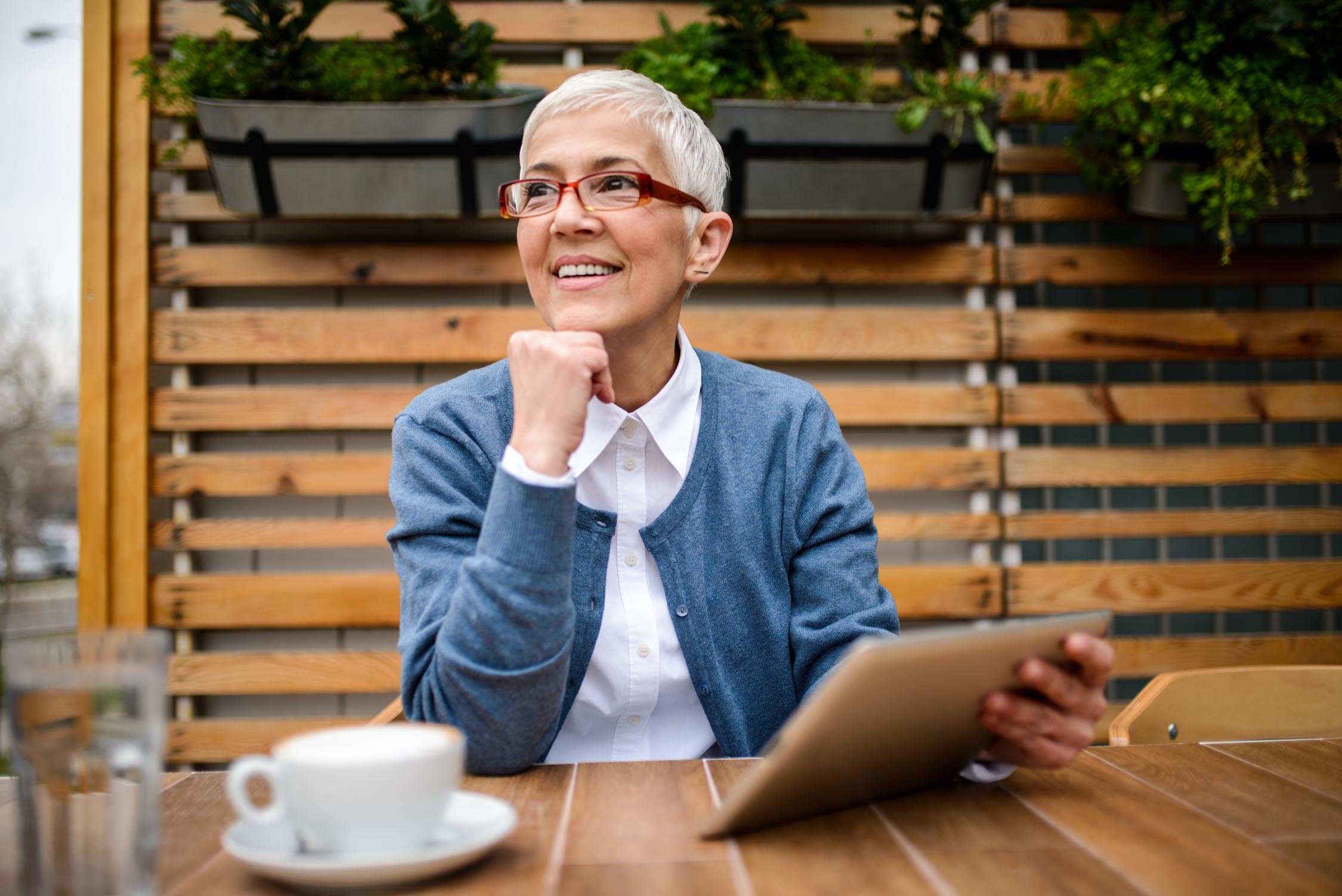 Smiling mature woman using digital tablet while drinking a coffee