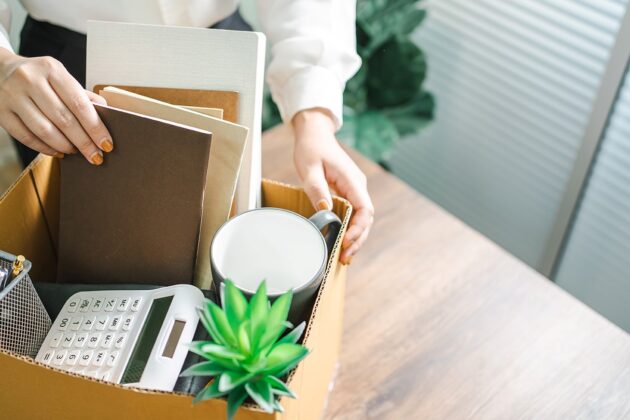 Professional Woman Packing A Box Of Office Belongings After Being Let Go From Her Job